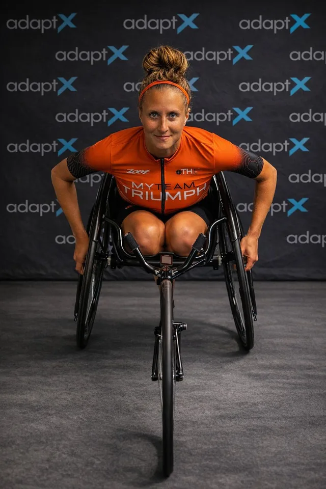 Brenda in her racing chair in front of an AdaptX backdrop