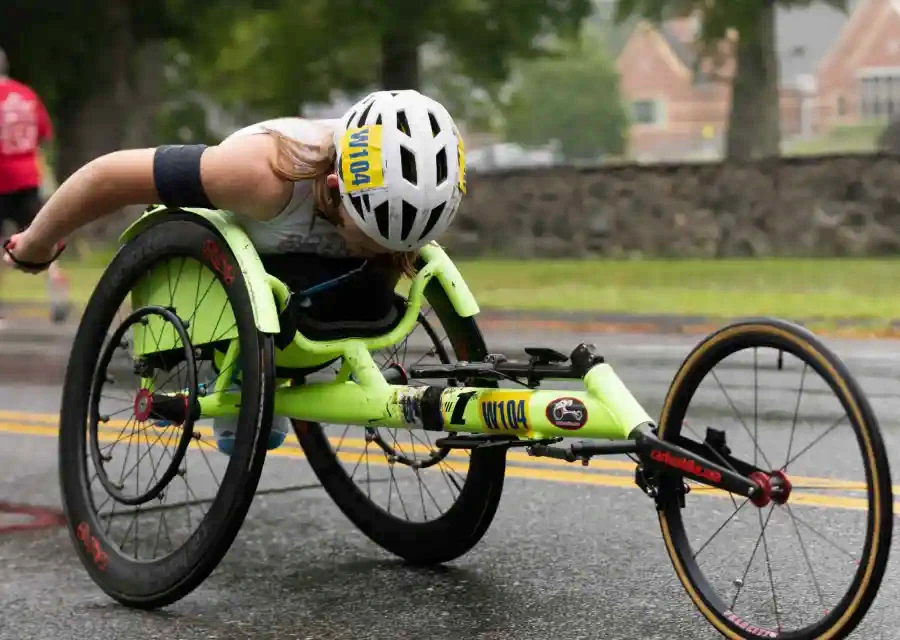 An athlete in a racing wheelchair competing on a wet road