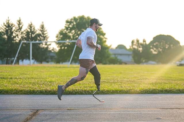 Sam Schaefer running on a road at sunrise on a running blade, a playing field behind him