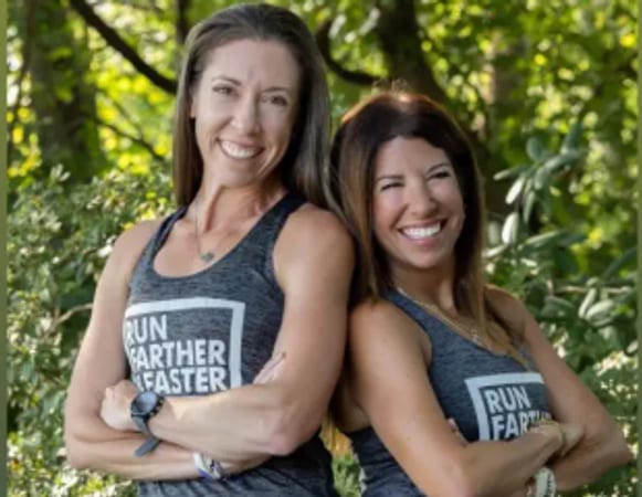 The two hosts of Run Farther and Faster standing together outdoors in team vests.