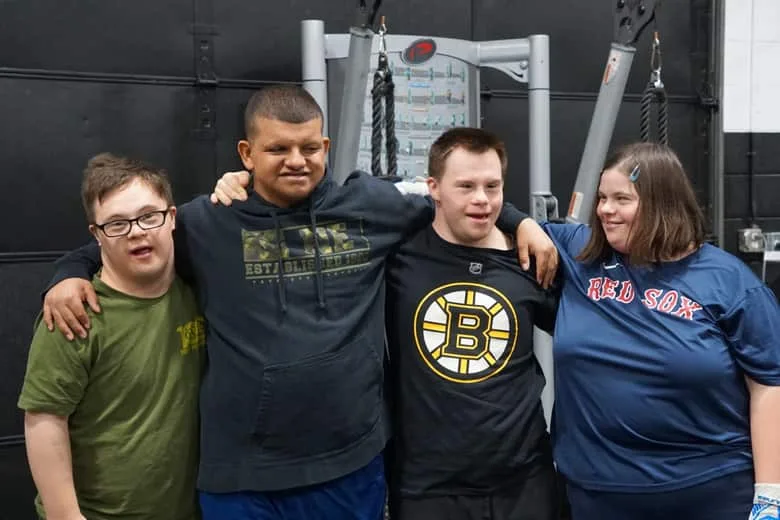 Four athletes standing arm in arm, smiling at the camera after a session.