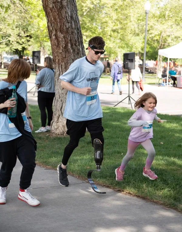 Brandon running on a blade alongside his younger sister at a Unified 5k