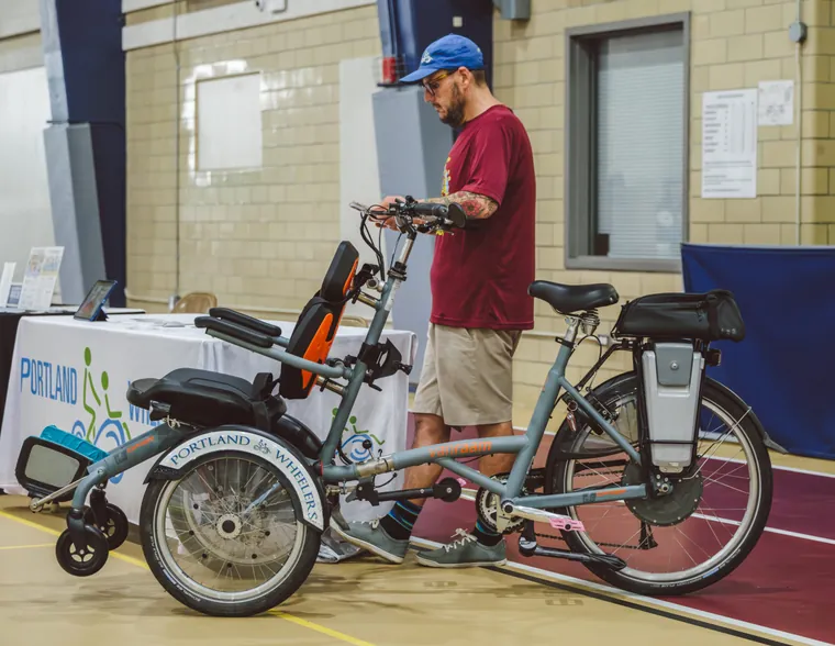An adaptive handcycle on show at the expo with an exhibitor beside it
