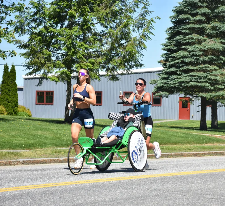 A duo team on the road, a runner pushing a green racing chair