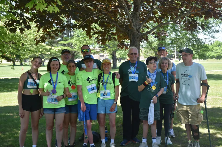 A group of participants in green shirts wearing their medals
