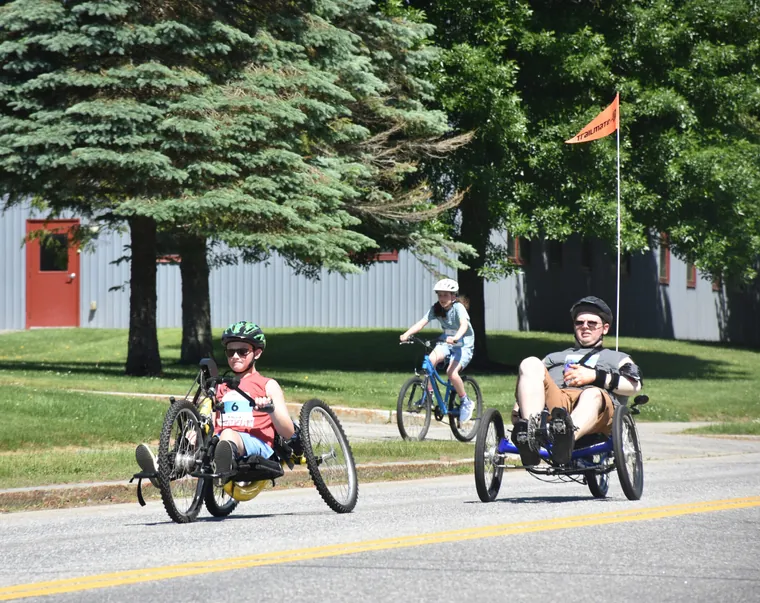 Handcyclists racing along the road past the trees