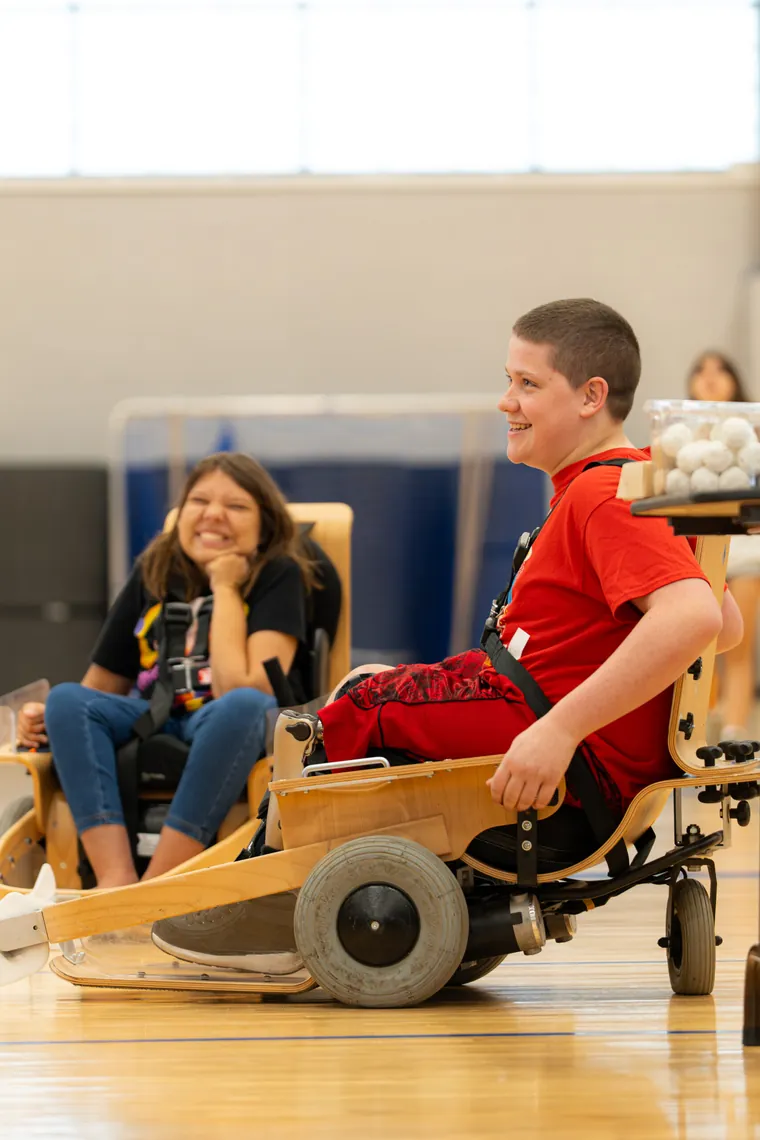 A young visitor trying an adaptive racing chair in the gym