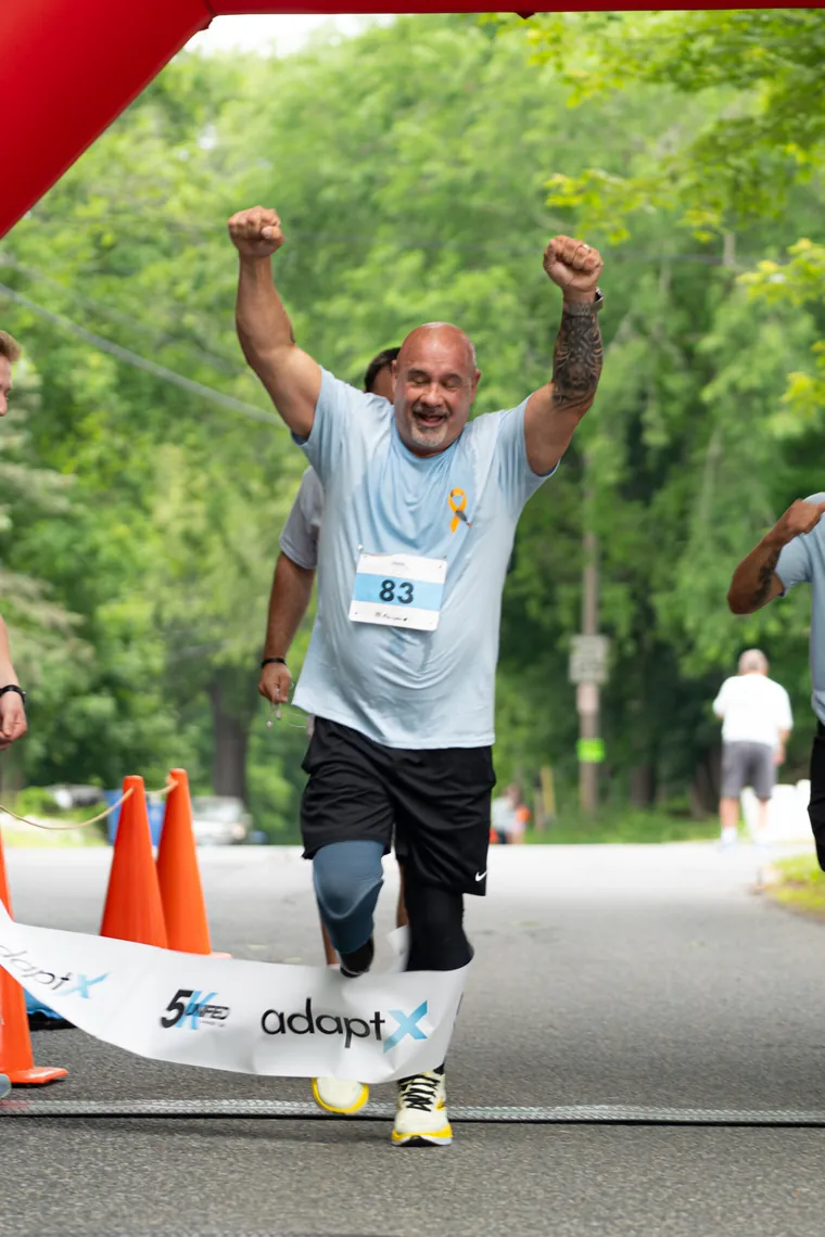 A finisher raising both arms as he crosses the line