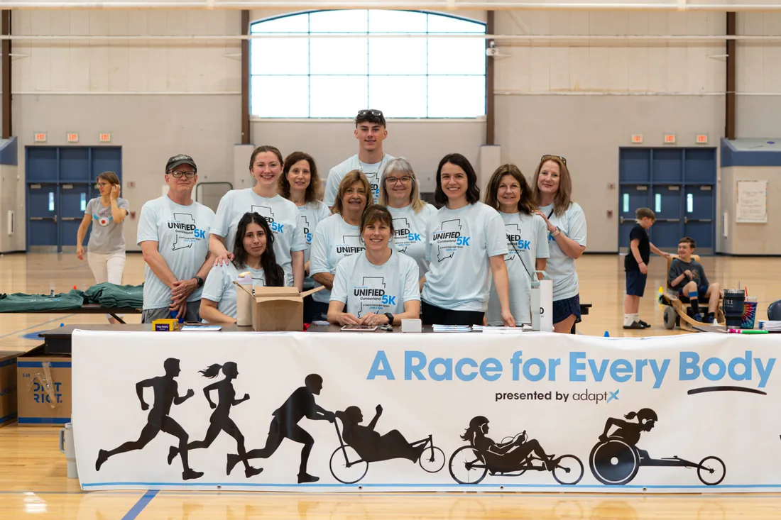 The volunteer team behind the A Race for Every Body banner in the school gym