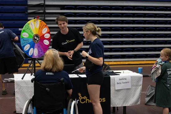 A Chair Champs prize wheel on a stand, with visitors taking part