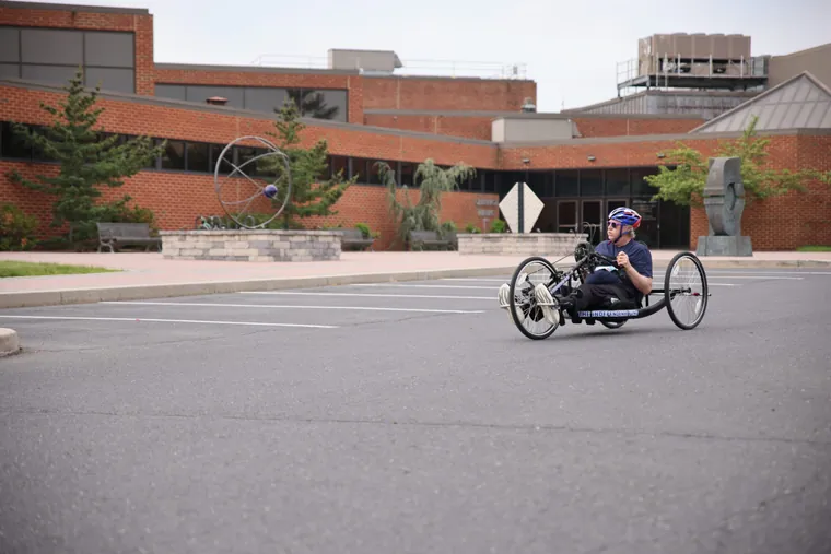 A handcyclist racing past the campus buildings