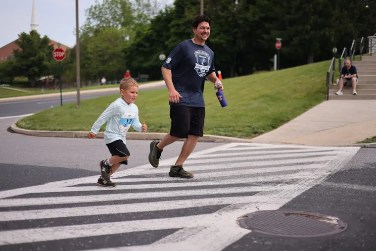 A young runner and an adult crossing a pedestrian crossing on the course