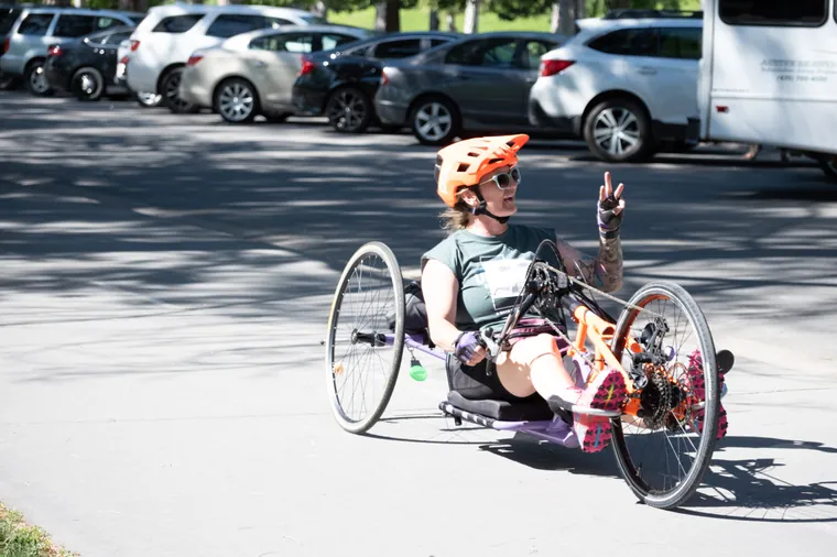 A racing wheelchair athlete raising a finger to the camera on the course