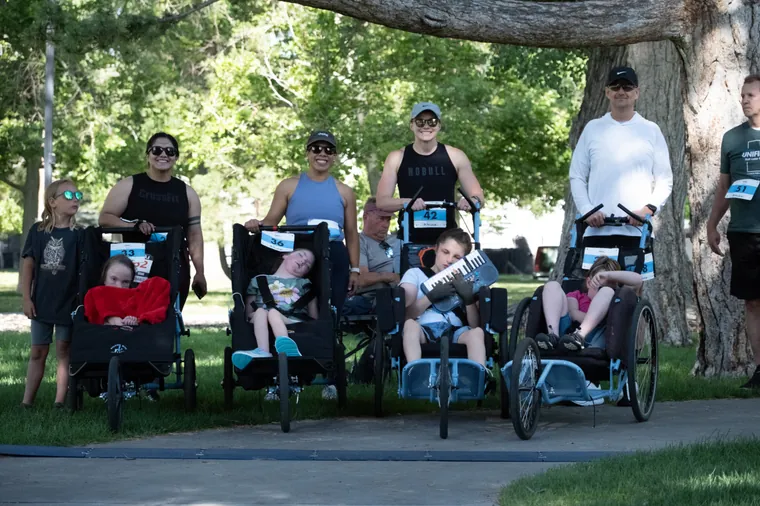 Families watching from the roadside with children in adaptive strollers