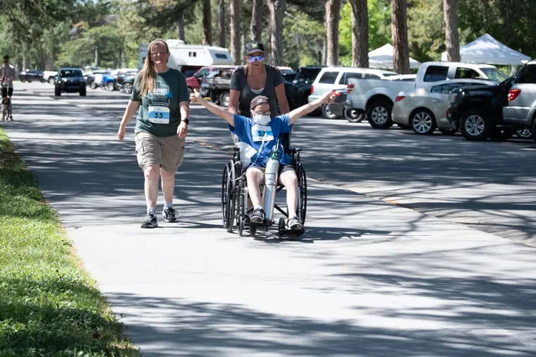 A volunteer pushing a participant in a wheelchair along the route