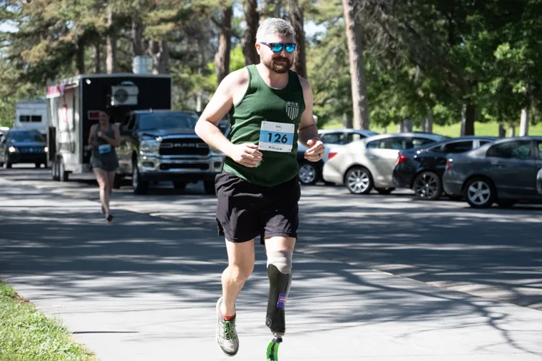 A runner racing on a blade prosthesis along the park road