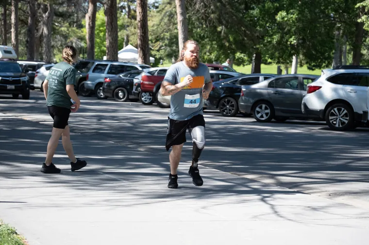 Two participants running together, one on a blade prosthesis