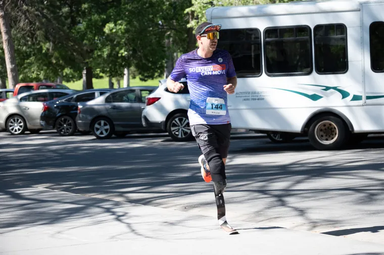 A runner on a blade prosthesis passing a parked shuttle bus