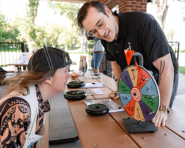 A visitor spinning a prize wheel at an exhibitor's table